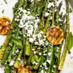 serving grilled asparagus with feta on an oval plate