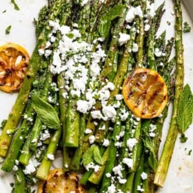 serving grilled asparagus with feta on an oval plate