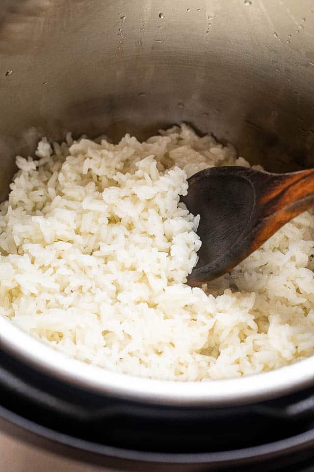 mixing jasmine rice with a wooden spoon in an instant pot