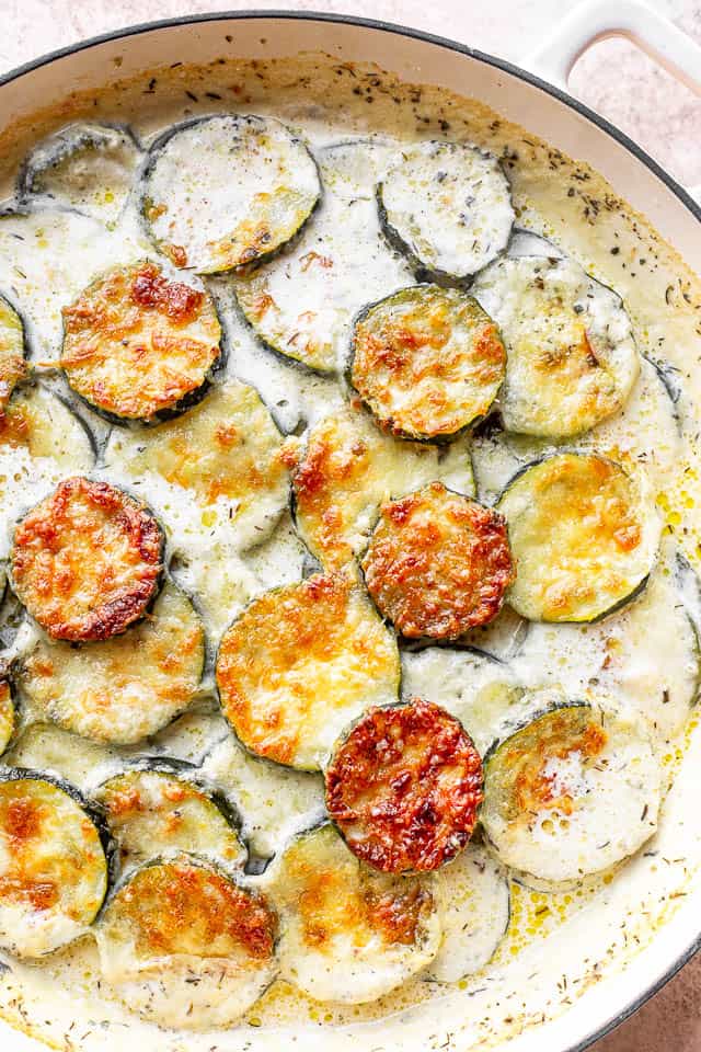 Top view of white round dutch oven with baked zucchini.