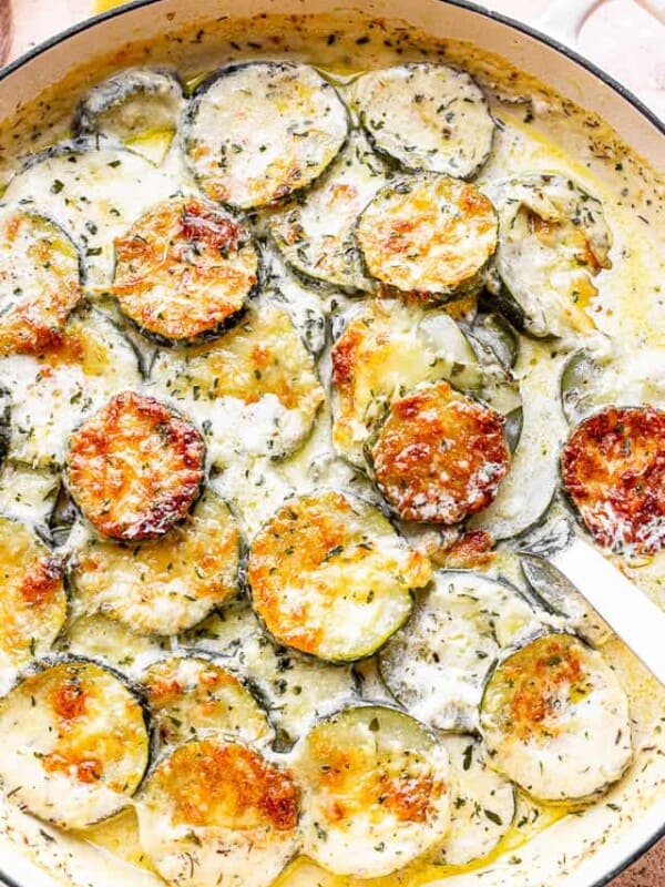 baked zucchini slices layered in a dutch oven and topped with cream mixture