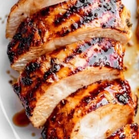 sliced chicken breast with grill marks set on a white plate