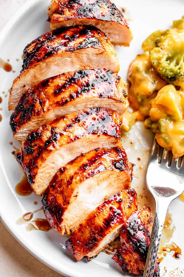 white dinner plate with sliced grilled chicken breast with grill marks.