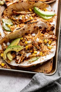 chicken carnitas tacos topped with avocado, onions, and corn