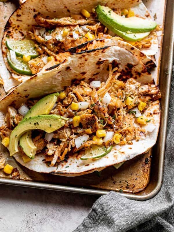 chicken carnitas tacos topped with avocado, onions, and corn