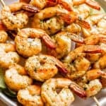 Grilled shrimp threaded onto skewers and arranged on a plate.