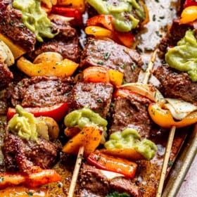 side view of grilled steak kabobs topped with guacamole