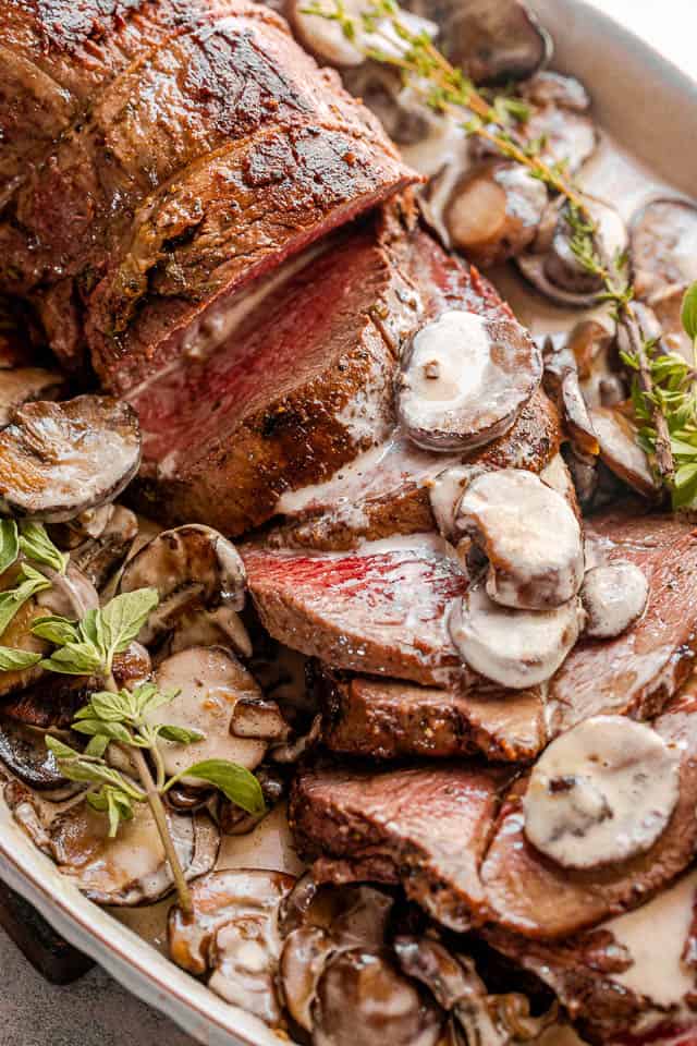 top view of sliced beef tenderloin on a serving plate topped with mushroom gravy