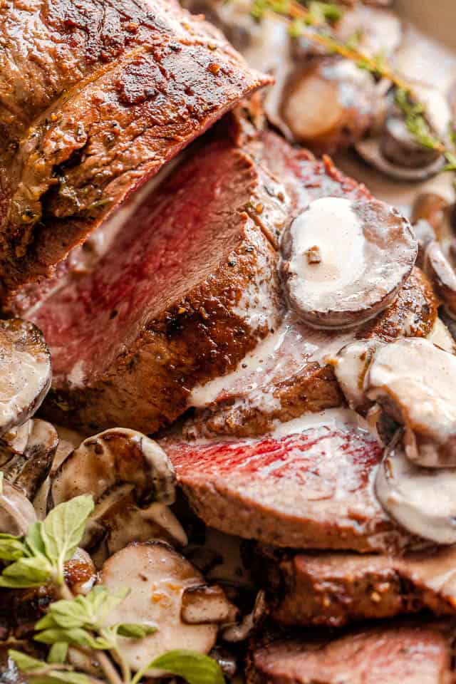 close up shot of a whole beef tenderloin sliced and topped with mushroom gravy