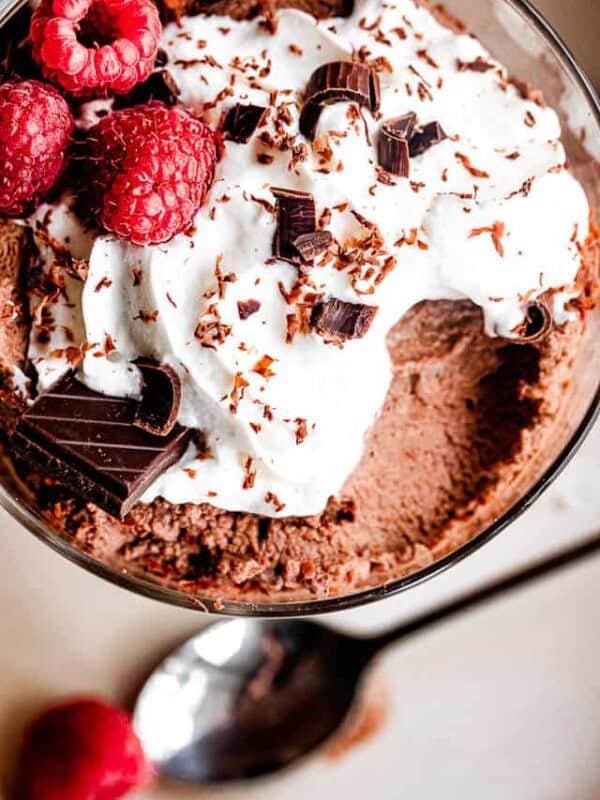 dessert dish filled with chocolate mousse, topped with whipped cream, raspberries, and chocolate shavings