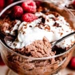 scooping out chocolate mousse from a glass dessert dish