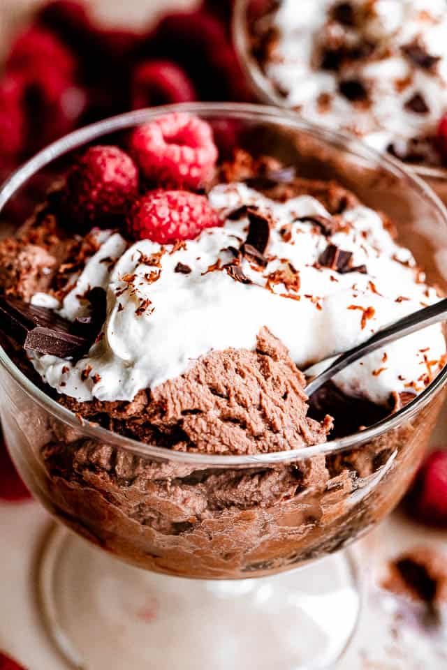 scooping out chocolate mousse from a glass dessert dish