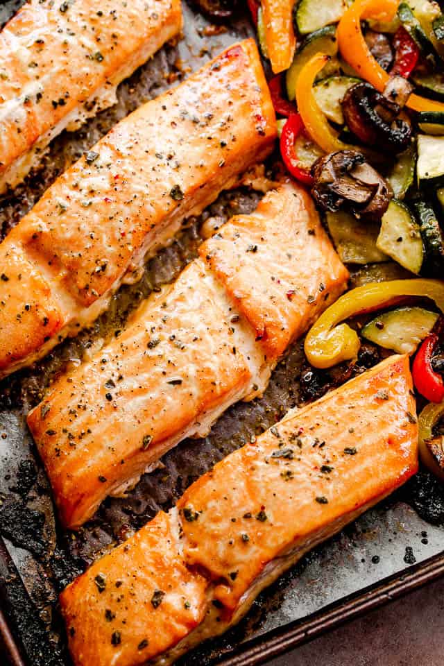 roasted maple teriyaki salmon fillets on a baking sheet with roasted veggies