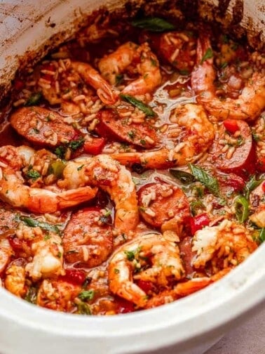 side shot of Jambalaya in a slow cooker studded with shrimp and garnished with green onions