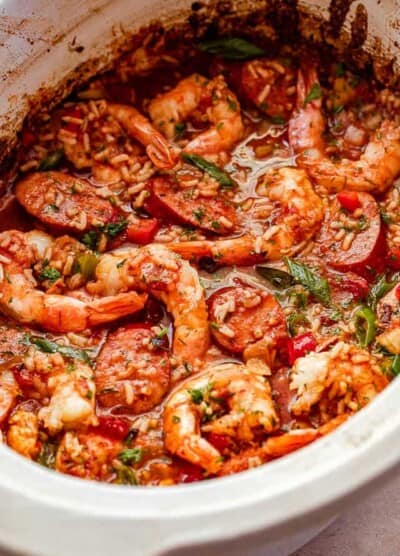 side shot of Jambalaya in a slow cooker studded with shrimp and garnished with green onions