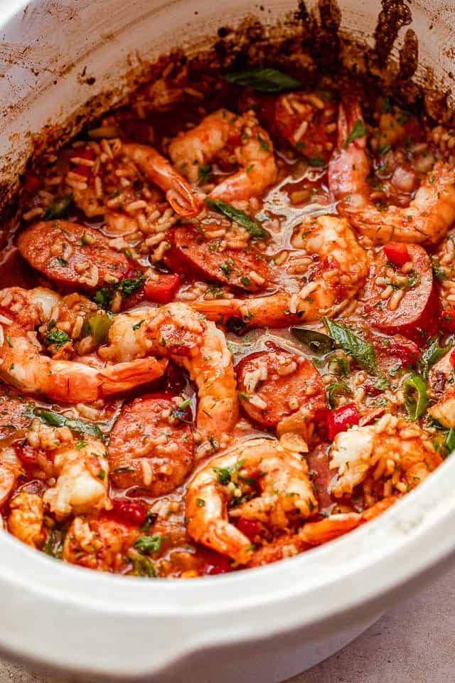 side photo of Jambalaya in a slow cooker studded with shrimp and garnished with green onions