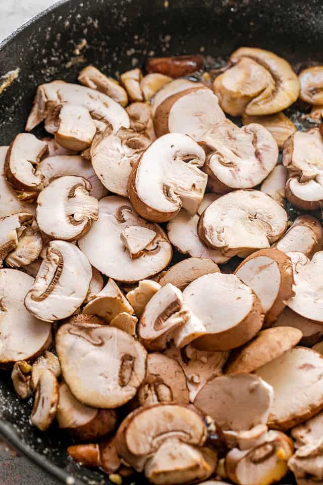 Make the most of your holiday meal with roasted beef tenderloin and homemade mushroom gravy. Simple, flavorful, and perfect for special occasions. Sliced mushrooms in a skillet.