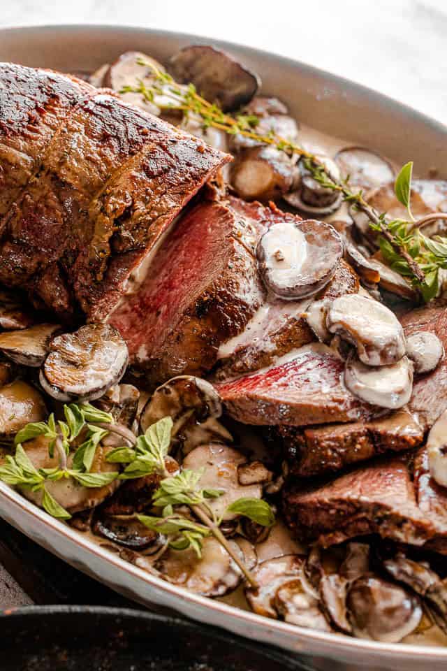 Make the most of your holiday meal with roasted beef tenderloin and homemade mushroom gravy. Simple, flavorful, and perfect for special occasions. Sliced beef tenderloin on a serving plate topped with mushroom gravy.