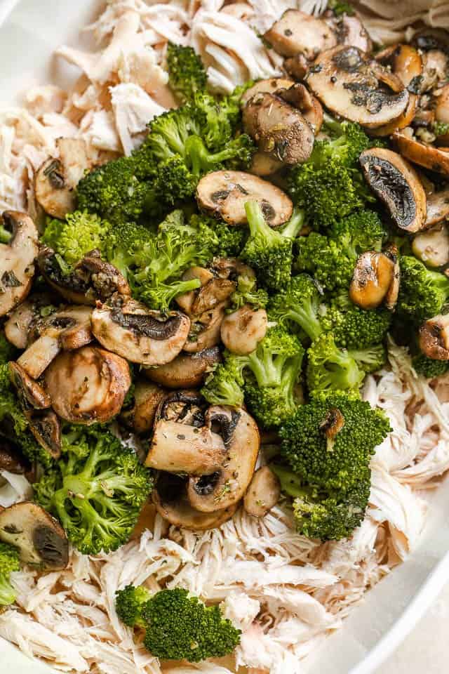 cooked broccoli and mushrooms set over shredded cooked chicken