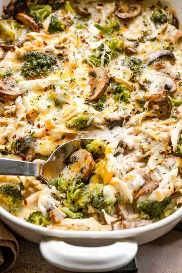 serving spoon scooping out chicken casserole from a white baking dish