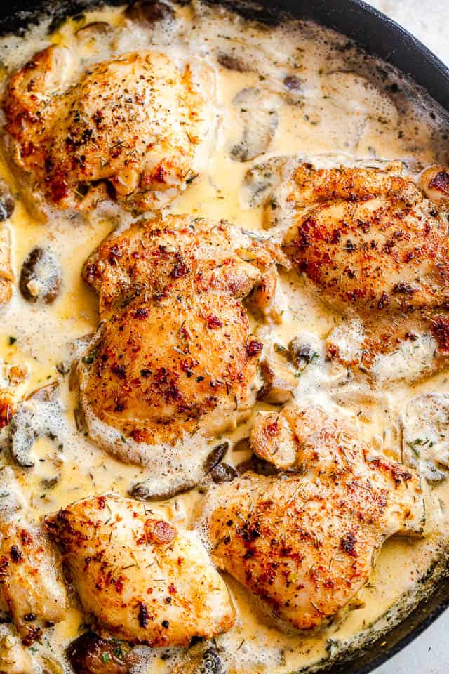 top close up shot of boneless chicken thighs cooking in a cream sauce with mushrooms