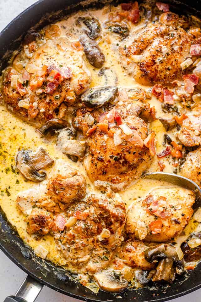 Top close-up shot of boneless chicken thighs cooking in a cream sauce with mushrooms