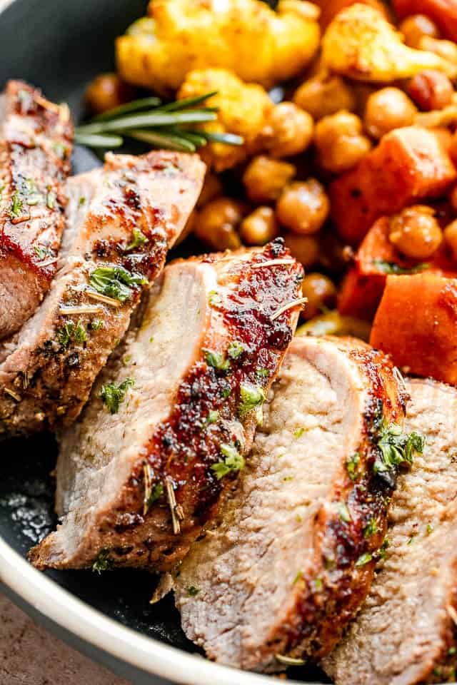 Up close image of sliced pork in a bowl served with chickpeas and sweet potatoes.