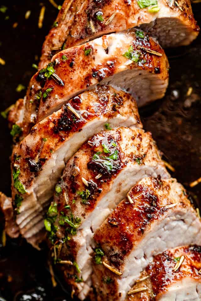 Close-up shot of slices of pork tenderloin on a dark background.