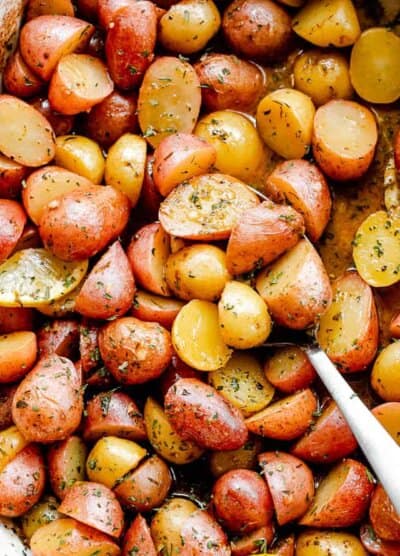overhead shot of halved yellow and red small potatoes in a baking dish