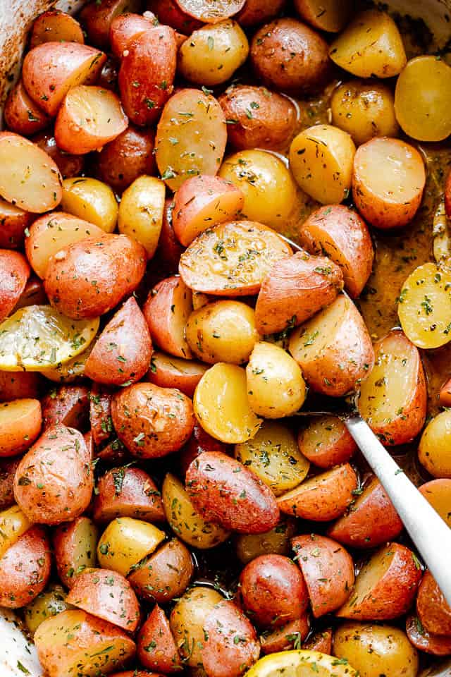 overhead shot of halved yellow and red small potatoes in a baking dish