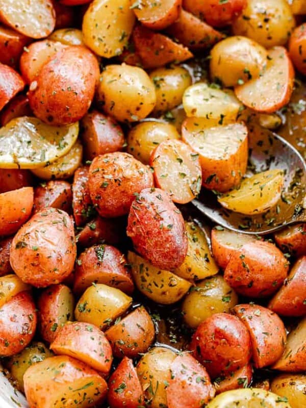 overhead shot of marinated halved yellow and red small potatoes in a baking dish