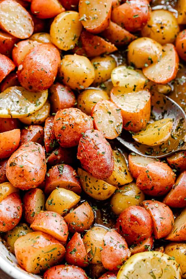 overhead shot of marinated halved yellow and red small potatoes in a baking dish