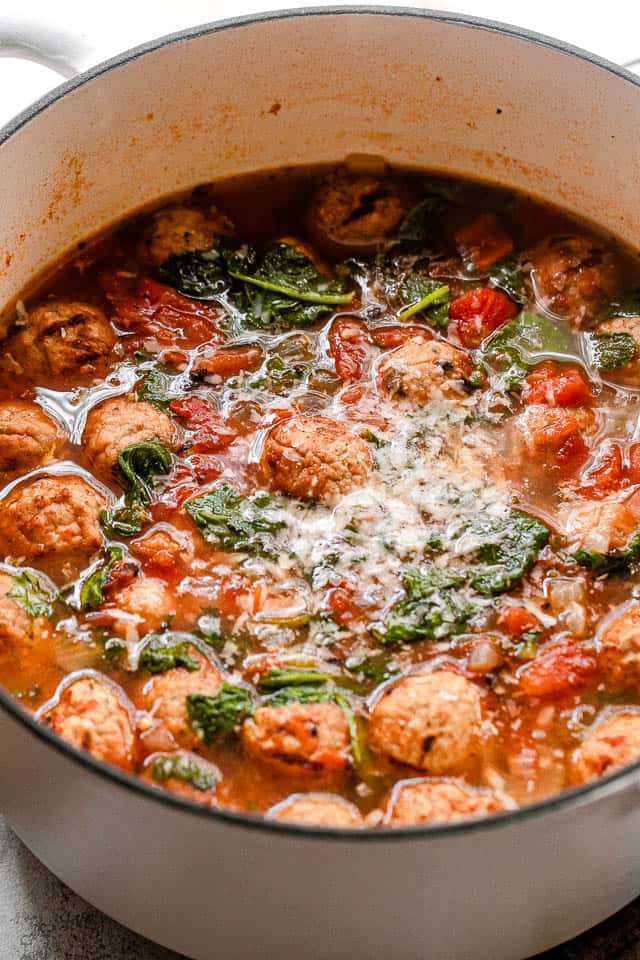 side shot of meatball soup in a white pot