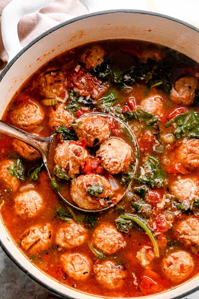 a pot of meatball soup with a ladle scooping out 4 meatballs