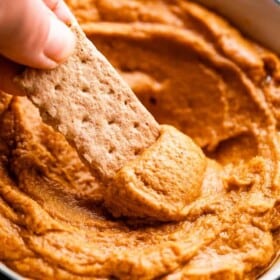 side shot of scooping out pumpkin peanut butter dip with a graham cracker