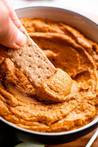 side shot of scooping out pumpkin peanut butter dip with a graham cracker