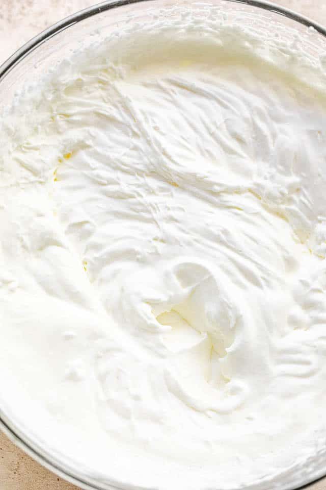 Overhead shot of freshly whipped heavy cream in a glass bowl.