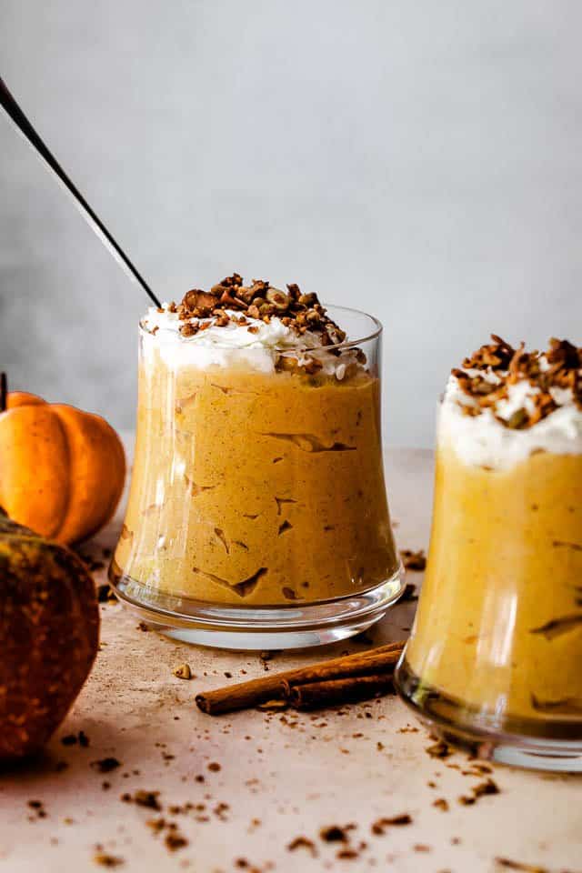 side shot of pumpkin mousse sprinkled with granola inside glass jars 