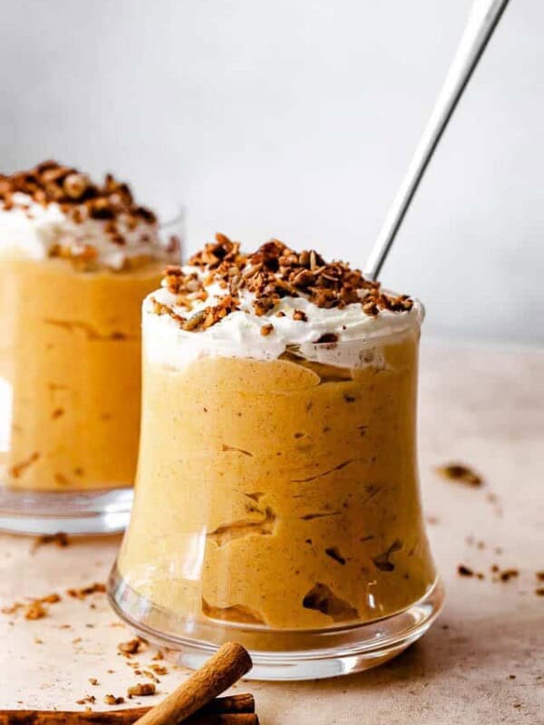 side shot of pumpkin mousse in a glass jar. mousse is sprinkled with granola on top.