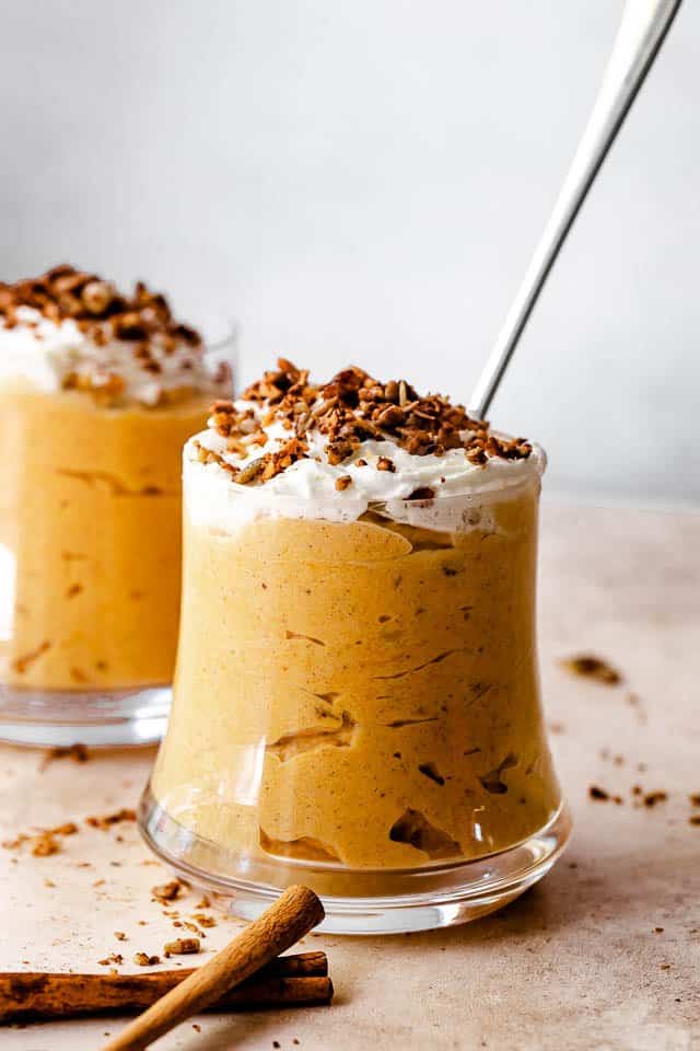 Side shot of pumpkin mousse in a glass jar, and sprinkled with granola on top.