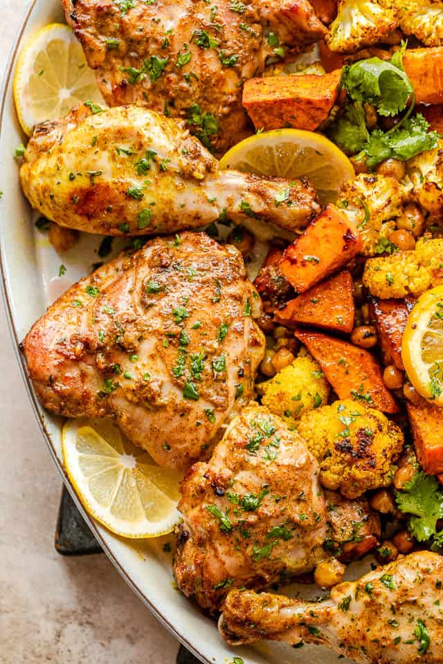 close up overhead shot of tandoori chicken served with cauliflower, sweet potatoes, and chickpeas