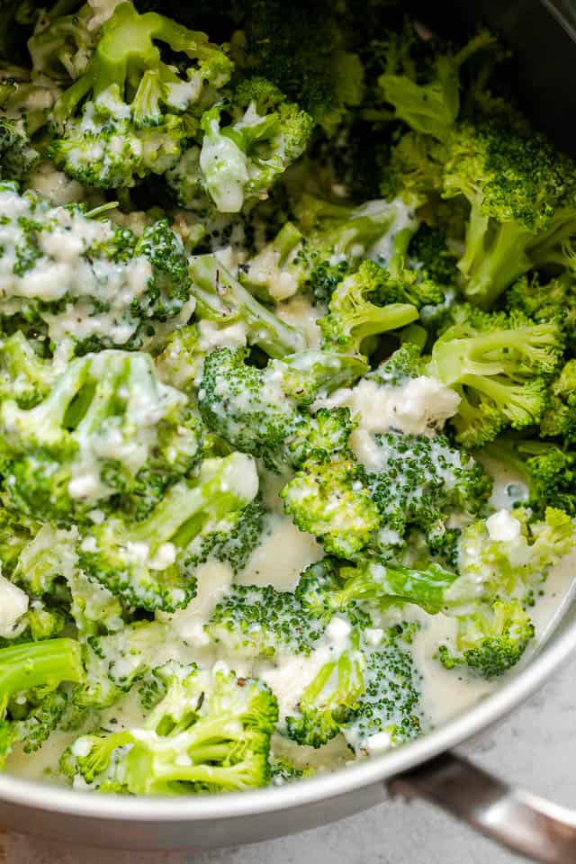 cooking pot with blanched broccoli tossed with cheese sauce