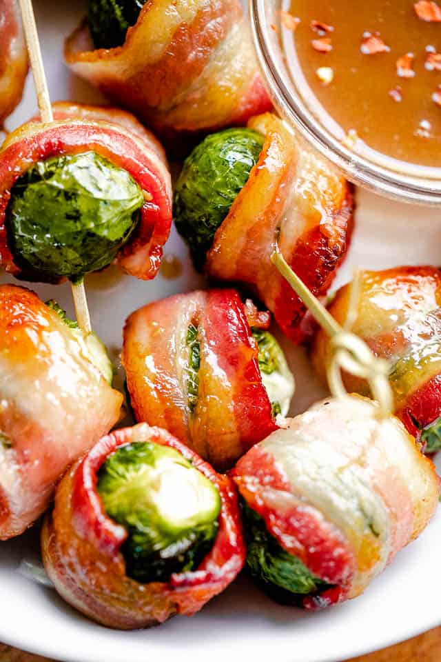 close up shot of bacon wrapped brussel sprouts in a white bowl