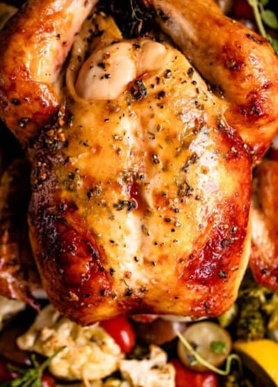 overhead close up shot of a whole roasted chicken served over veggies
