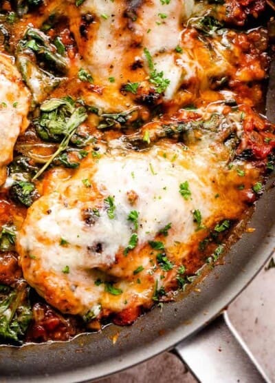 overhead close up shot of a skillet with cooked chicken breasts in tomato sauce