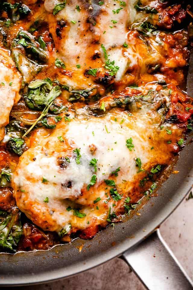 overhead close up shot of a skillet with cooked chicken breasts in tomato sauce