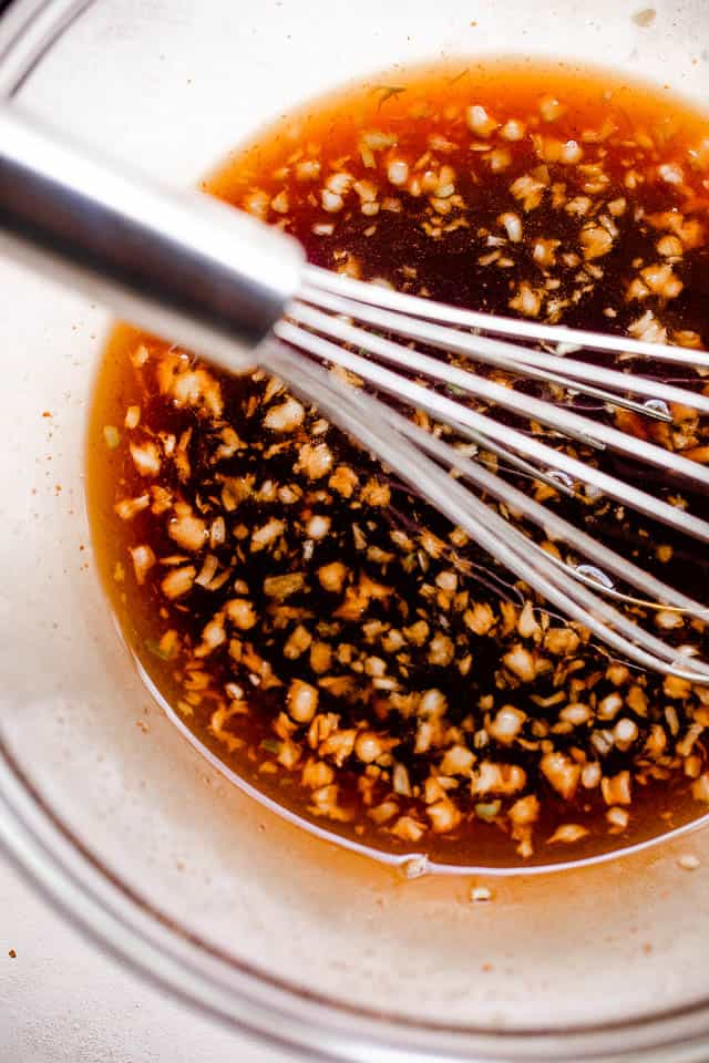 Whisking honey garlic sauce in a glass mixing bowl.
