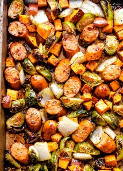 overhead shot of a sheet pan with cooked andouille sausage, brussels sprouts, and sweet potatoes
