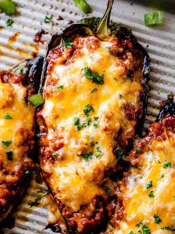 Close up of stuffed poblano peppers filled with chili and topped with melted cheese.