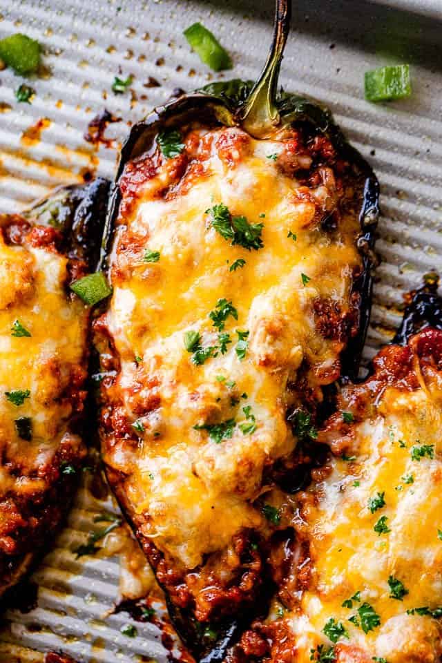 close up shot of chili stuffed poblano peppers topped with melty cheese